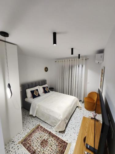 a white bedroom with a bed and a television at Pietro Guesthouse 3 in Tirana
