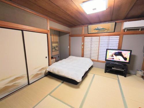 Dormitorio pequeño con cama y TV en season guest house, en Tokio