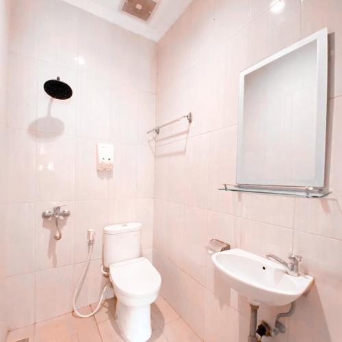 a white bathroom with a toilet and a sink at DINASTY STYLE HOTEL SOLO in Bonorejo