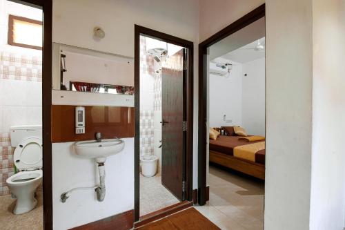 a bathroom with a sink and a toilet and a bed at Manora Residency in Puducherry