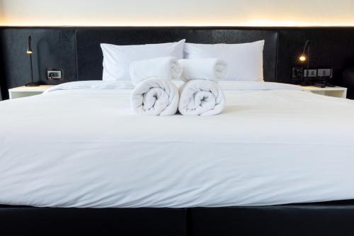 two rolls of towels on top of a white bed at NANEE Phra Singh in Chiang Mai