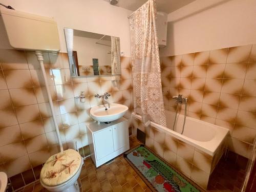 a bathroom with a sink and a toilet and a tub at Apartmani Ružić in Jadranovo