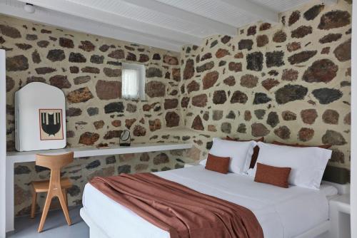 a bedroom with a bed in a room with stone walls at Iliana Olive Branch in Adamantas