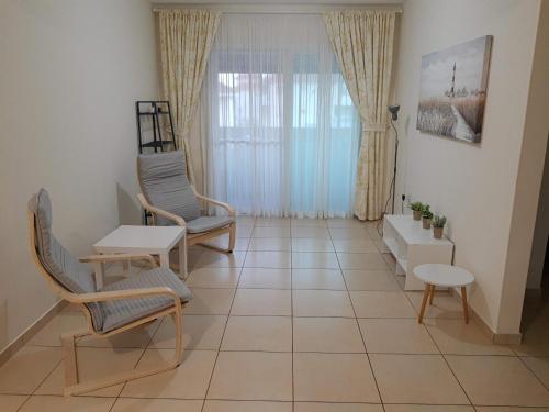 een woonkamer met stoelen, een tafel en een raam bij Larnaca Xylophagou 2-bedroom apartment with a shaded terrace in Xylophaghou