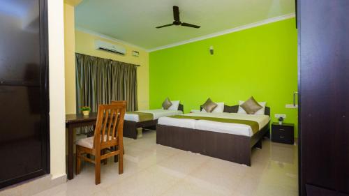 1 Schlafzimmer mit 2 Betten und einer grünen Wand in der Unterkunft SPRING DE GOA in Porvorim