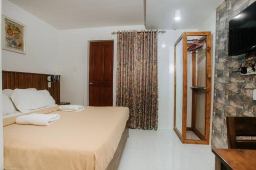 a hotel room with a bed and a television at Delle Suites in General Santos