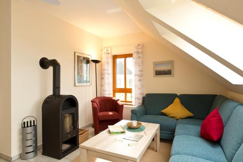 a living room with a blue couch and a wood stove at Haus Sarah 3 Am Lorenweg 10 in Göhren-Lebbin