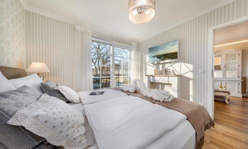 Un dormitorio con una gran cama blanca y una ventana en Villa Strandblick Zingst, en Zingst