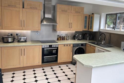 ロンドンにあるWandsworth, South London Deluxe King Room 4の木製のキャビネットとコンロ付きオーブンを備えたキッチン