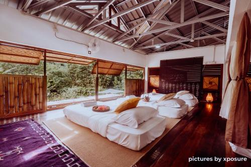 three beds in a room with large windows at Tirtha Quddus Farmstay in Bentong