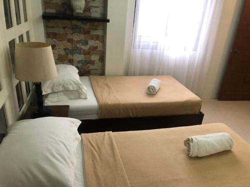 a hotel room with two beds and a lamp at Delle Suites in General Santos