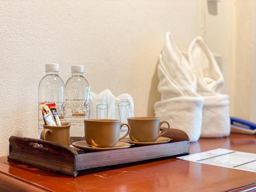 a wooden table with two cups and bottles of water at Rim Tara Residence Patan in Chiang Mai