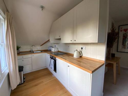 a kitchen with white cabinets and a wooden counter top at Ipsley Lodge Apartment Surrey Hills in Farnham