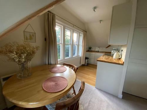 a kitchen with a wooden table with chairs and a dining room at Ipsley Lodge Apartment Surrey Hills in Farnham