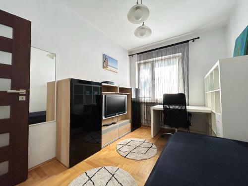 un salon avec une télévision et un bureau avec une chaise dans l'établissement Apartament Ponikwoda, à Lublin