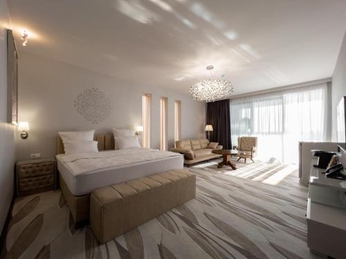 Villa Elysium Park & SPA في باتومي: غرفة نوم بسرير واريكة في غرفة