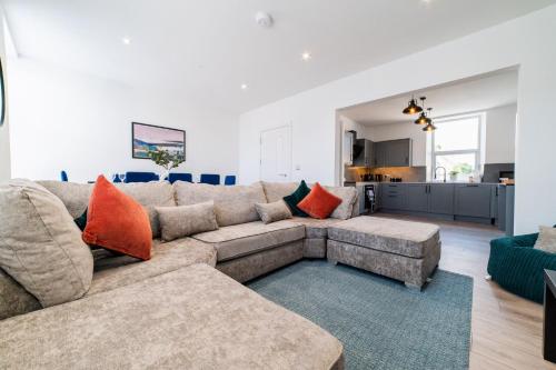 a living room with a large couch and orange pillows at The Dunes, Porthcawl in Newton