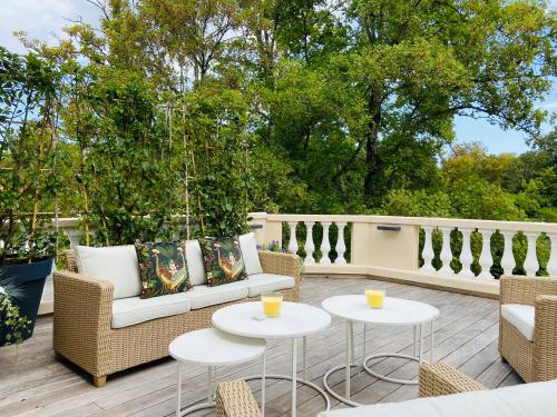 a patio with two tables and wicker chairs at L’orée du bois des rois in Ury