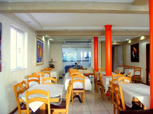 a dining room with tables and chairs and orange columns at Pousada Águas do Forte in Cabo Frio