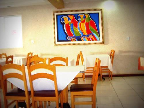 a dining room with a table and chairs and a painting of parrots at Pousada Águas do Forte in Cabo Frio