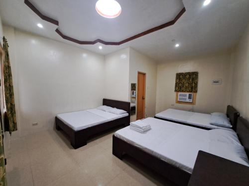 a bedroom with two beds and a ceiling at Lagnason's Place in Oslob