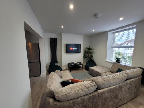 a living room with a large couch and a tv at The Dunes, Porthcawl in Newton
