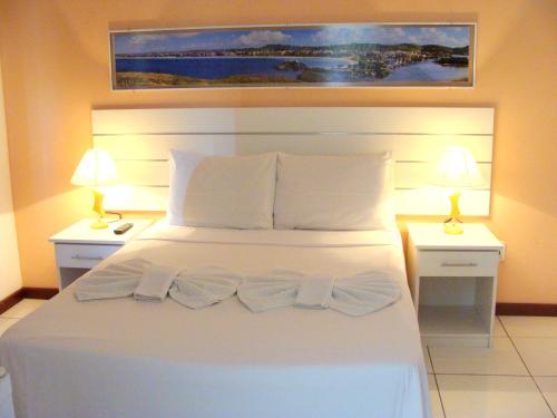 a bedroom with a white bed with two nightstands and two lamps at Pousada Águas do Forte in Cabo Frio