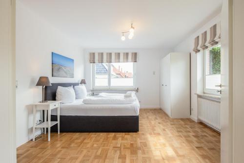 um quarto com uma cama, uma mesa e 2 janelas em Appartement Olivia em Westerland