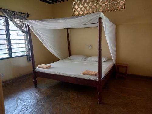 a bed with a canopy in a room at Malaika Holiday Villas in Diani Beach