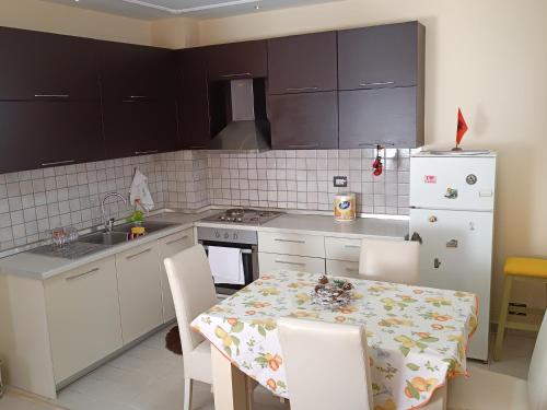 a kitchen with a table and a white refrigerator at Sermi's House in Shkodër