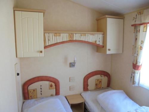 a small room with two beds and a shelf at Northshore: Salisbury NS:- 8 Berth, 3 bedrooms in Lincolnshire