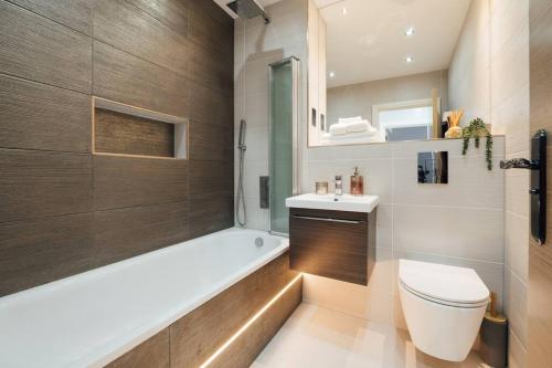 a bathroom with a tub and a toilet and a sink at Inviting 2 Bedroom House in Dorking in Dorking