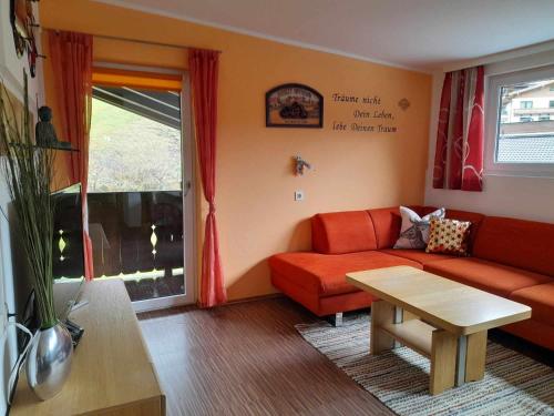 a living room with a red couch and a table at Hotel-Pension Wolfgang in Saalbach Hinterglemm