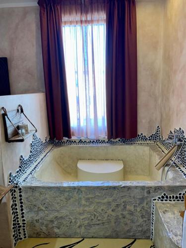 a large bath tub with a window in a bathroom at Hotel Bella 'Mbriana in Follonica