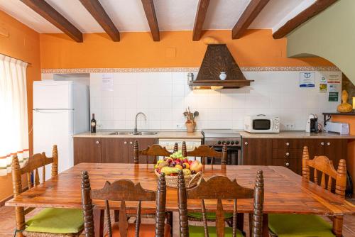 una cucina con tavolo in legno e sedie e una cucina con lavandino di CASA RURAL ANGELITA a Rosell