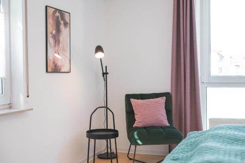 a bedroom with a green chair and a lamp at FiNEST Design Stuttgart Airport Messe Stadtbahn U7 in Ostfildern