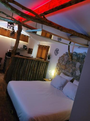 1 dormitorio con cama blanca y pared de piedra en LOVE Room Danslesbois avec spa, en Cuges-les-Pins