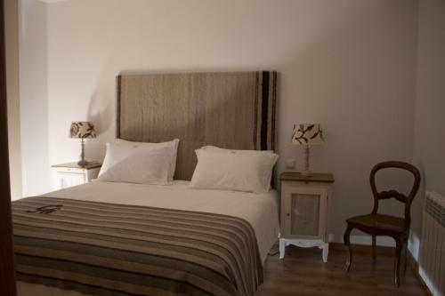 um quarto com uma cama branca com uma cadeira e uma cadeira em Casa Avó Chiquinha em Montalegre