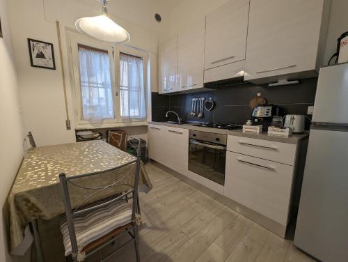 uma cozinha com armários brancos, uma mesa e um frigorífico em Il Centro em Camaiore