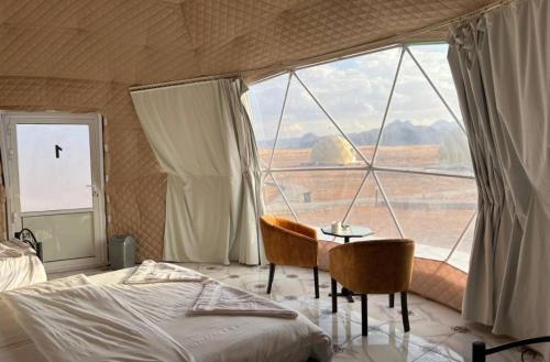 a bedroom with a bed and a table and a large window at Mishari Wadi Rum camp in Disah