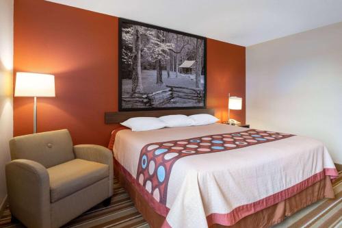 a small hotel room with a bed and a chair at Super 8 by Wyndham Mattoon in Mattoon