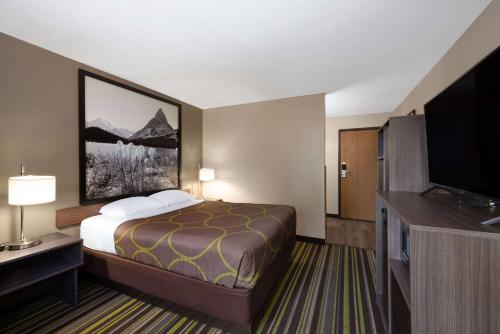 a hotel room with a bed and a flat screen tv at Super 8 by Wyndham Belgrade/Bozeman Airport in Belgrade