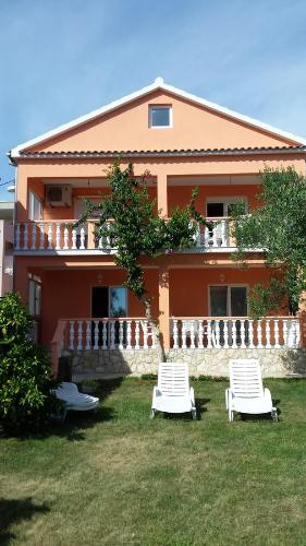 a house with two lawn chairs in front of it at Apartments Igor in Bibinje