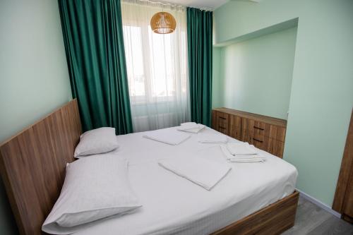 a bedroom with a white bed with green curtains at Hotel Tigran Mets Yerevan in Yerevan