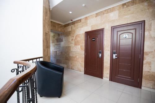 a hallway with a wooden door and a black chair at Hotel Tigran Mets Yerevan in Yerevan