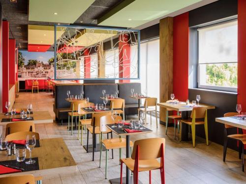 un restaurante con mesas y sillas de madera y paredes rojas en Ibis Milano Fiera, en Lainate