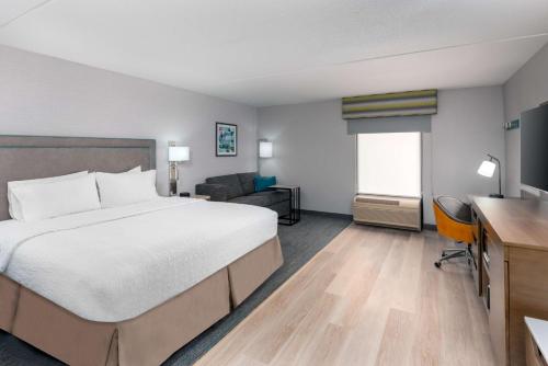 una camera d'albergo con letto e divano di Hampton Inn Hartford Airport a Windsor Locks