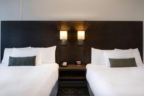 a hotel room with two beds and a table between them at Days Inn by Wyndham Victoria Airport Sidney in Sidney