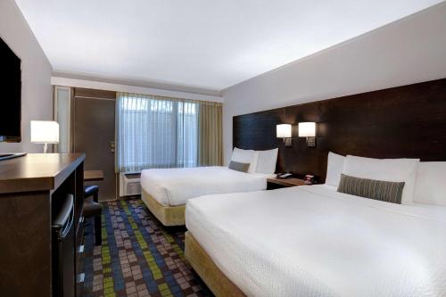a hotel room with two beds and a television at Days Inn by Wyndham Victoria Airport Sidney in Sidney