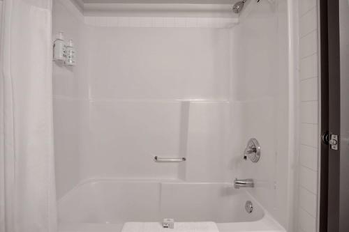 a white bathroom with a tub and a shower at Days Inn by Wyndham Victoria Airport Sidney in Sidney